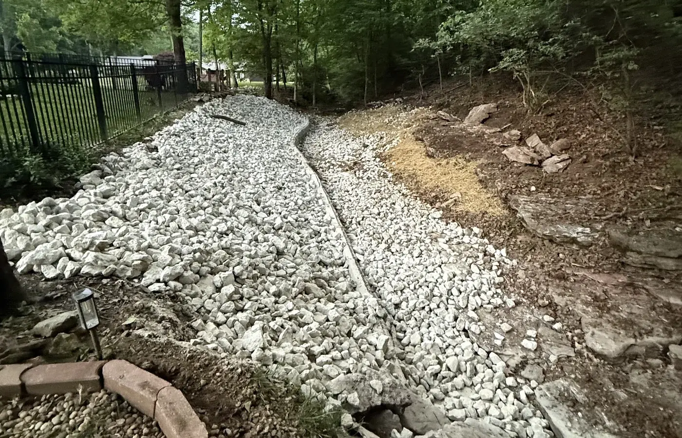 A closer view along the same rock drainage run, showing the rip-rap and the graded slope above it